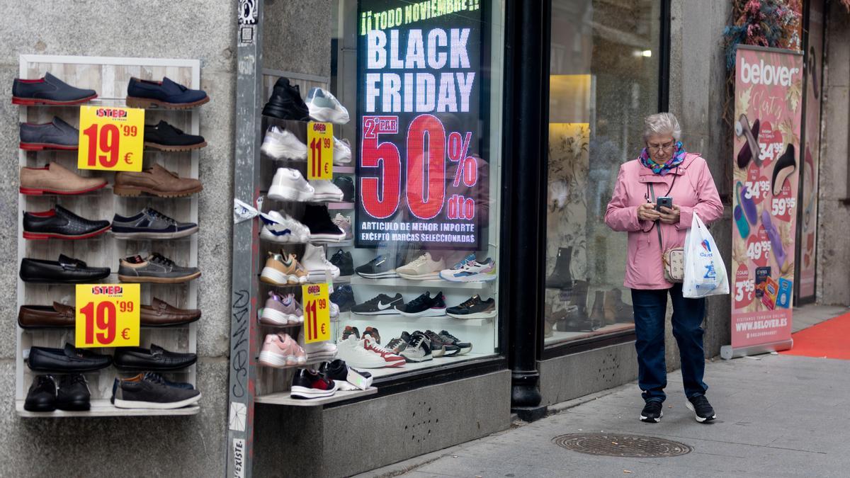 Una mujer pasa por delante de una tienda que anuncia un cartel publicitario del ‘Black Friday’.