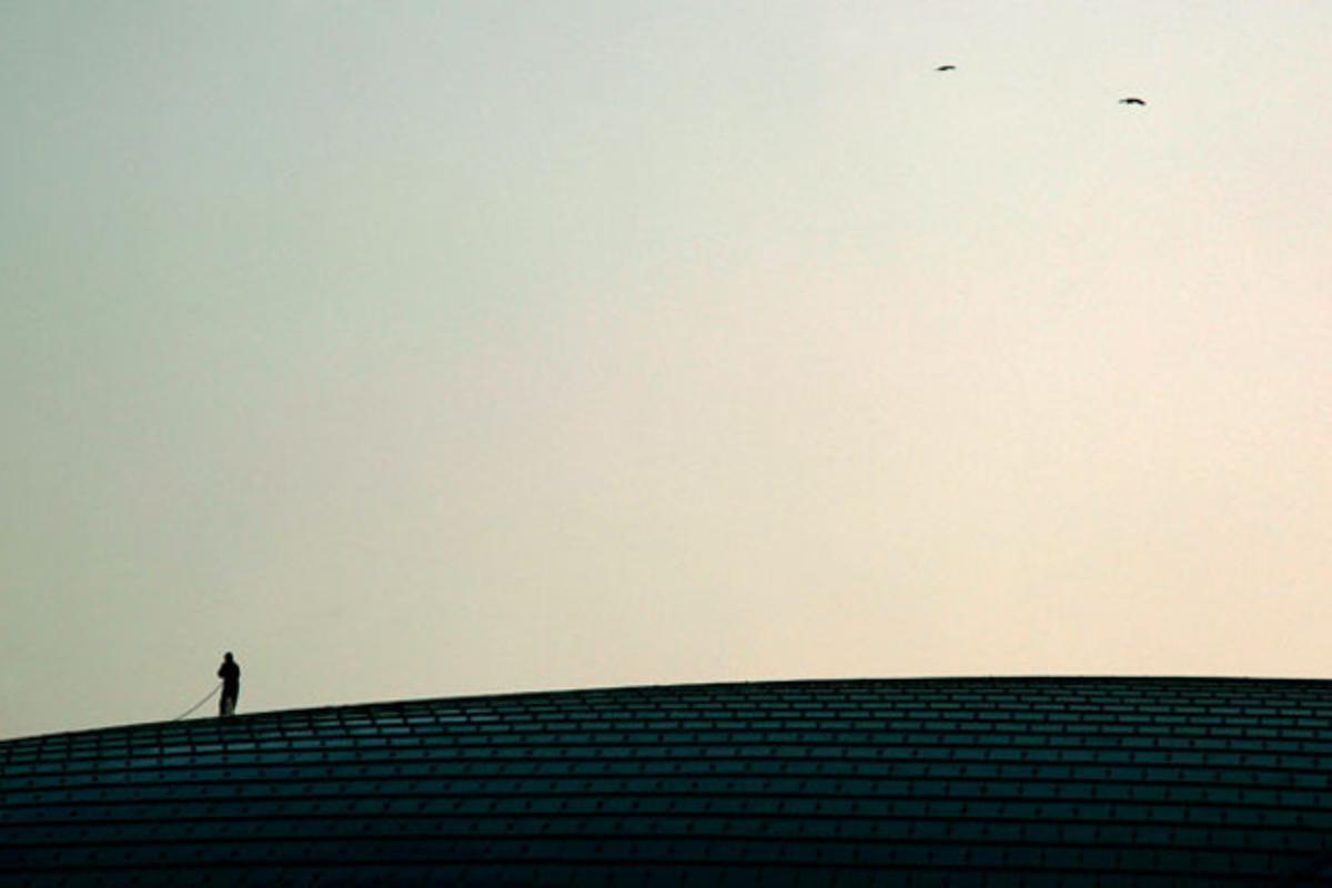 Un treballador neteja la teulada del Gran Teatre Nacional de Pequín (Xina), també anomenat The Egg.