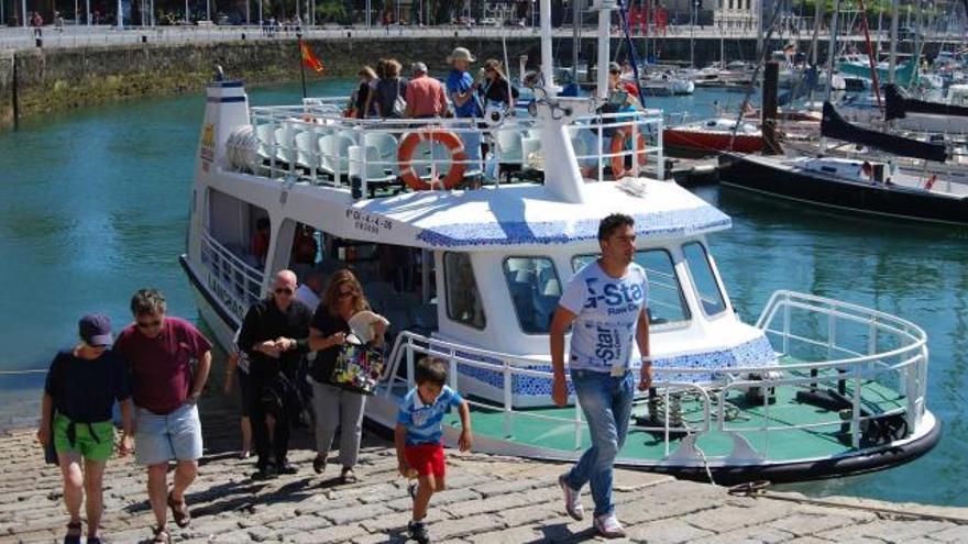 Unos turistas bajan del barco, ayer, tras el paseo por la bahía gijonesa. / C.A