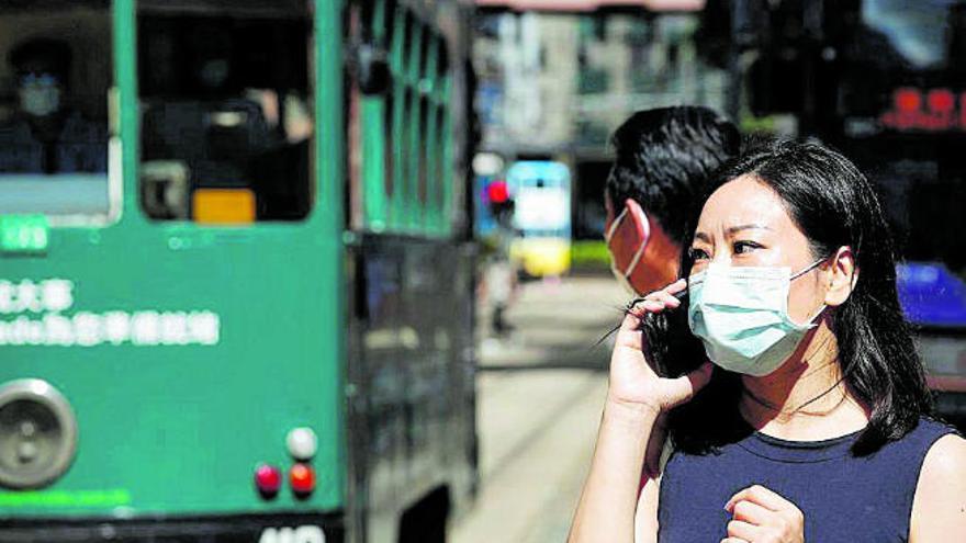 Una mujer se protege con mascarilla en las calles de Hong Kong.