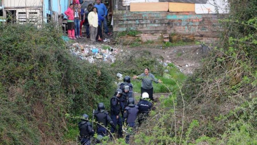 Una mujer se interpone entre un grupo de agentes de la Policía Nacional que intenta acceder al poblado de O Vao      durante este operativo.  // Gustavo Santos