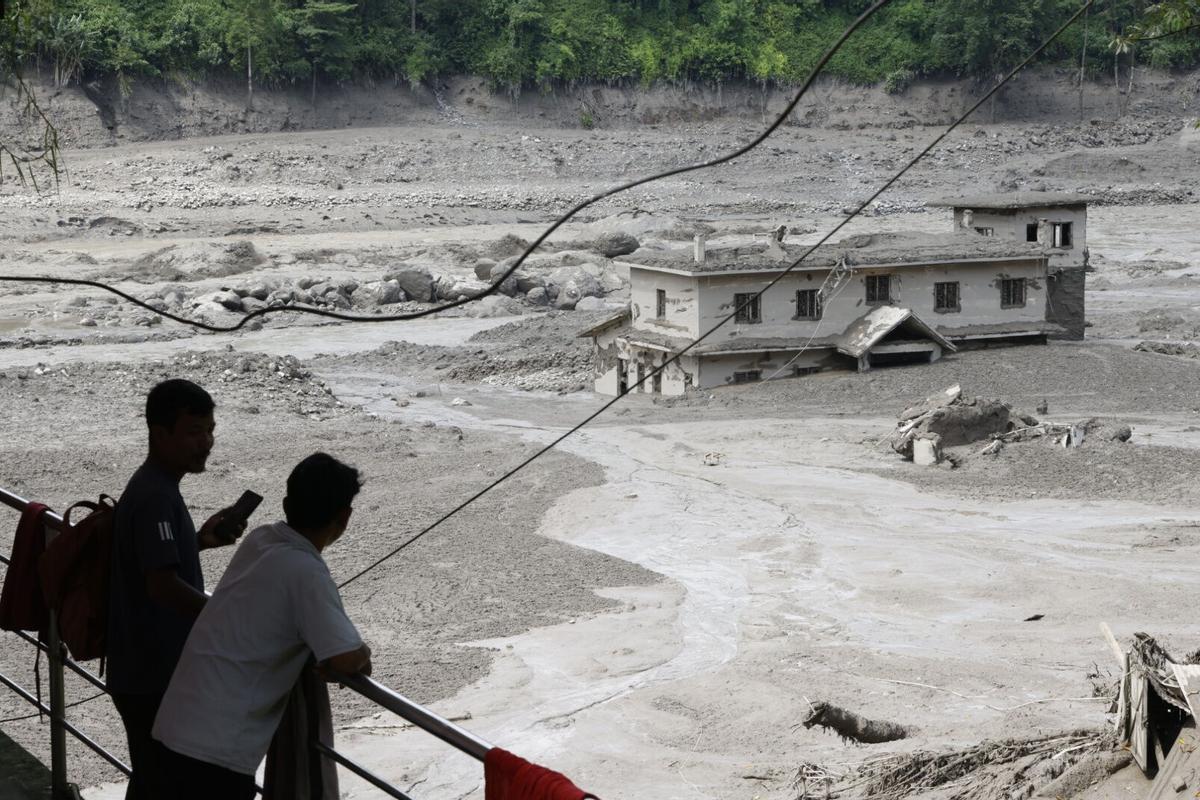 Varias personas observan cómo las aguas de la inundación arrasan Trishuli Bazar tras una crecida repentina, en el distrito de Nuwakot, Nepal. Varias personas observan cómo las aguas de la inundación arrasan Trishuli Bazar tras una crecida repentina, en el distrito de Nuwakot, Nepal.