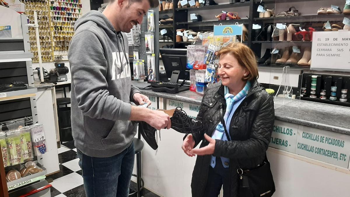 Alejandro Blanco entrega un par de zapatos a Mari Nieves Peña, en su negocio, a punto de echar el cierre