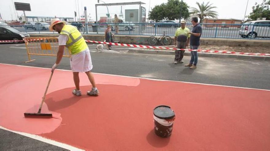 Un operario extiende la pintura especial del carril bici en presencia del edil Fernando Marcos, ayer.