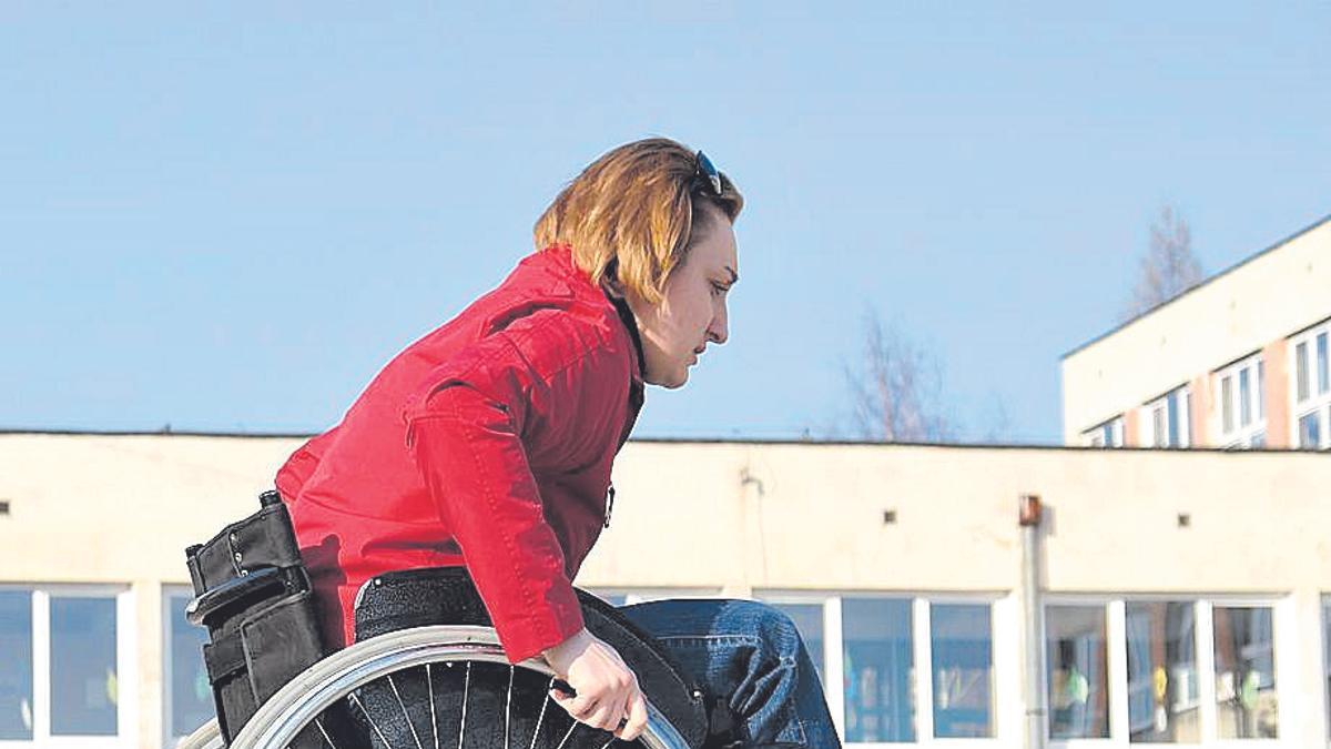 Una mujer asciende por una rampa con su silla de ruedas.