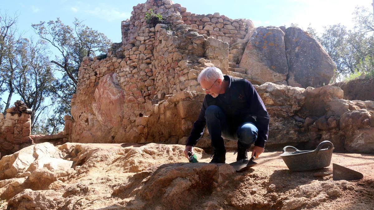 L'arqueòleg Joan Llinàs netejant l'espai del jaciment que va acollir la sala principal del castell, amb la torre circular al fons.