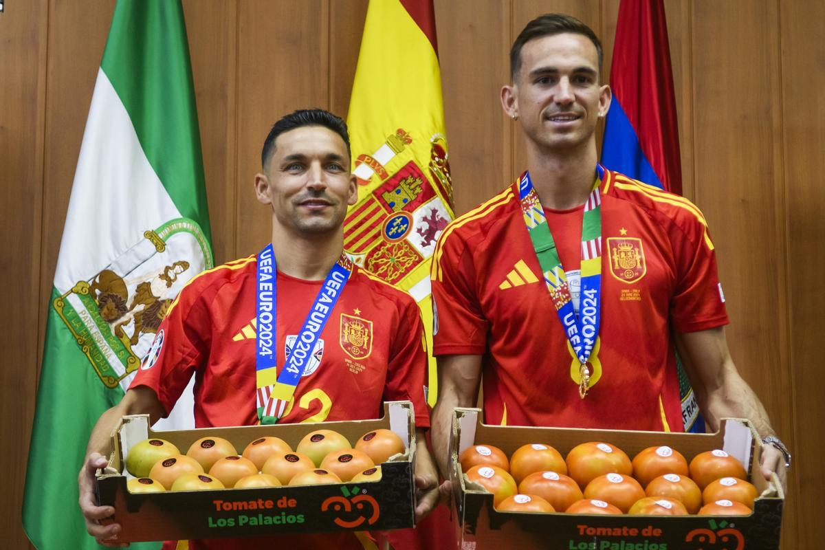 LOS PALACIOS Y VILLAFRANCA (SEVILLA), 16/07/2024.- Los palaciegos Jesús Navas (i) y Fabián Ruiz (d), jugadores de la selección española de fútbol, durante el homenaje recibido en su pueblo natal por cientos de vecinos que les han ido a recibir al Ayuntamiento, donde han recibido su peso en kilos de tomate. EFE/ EFE/ Raúl Caro