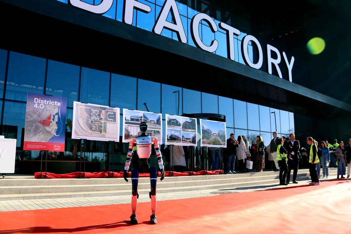 Un robot dona la benvinguda als presents a l'acte de col·locació de la primera pedra de l'ampliació del DFactory Barcelona amb diverses imatges virtuals al fons de com quedarà el projecte