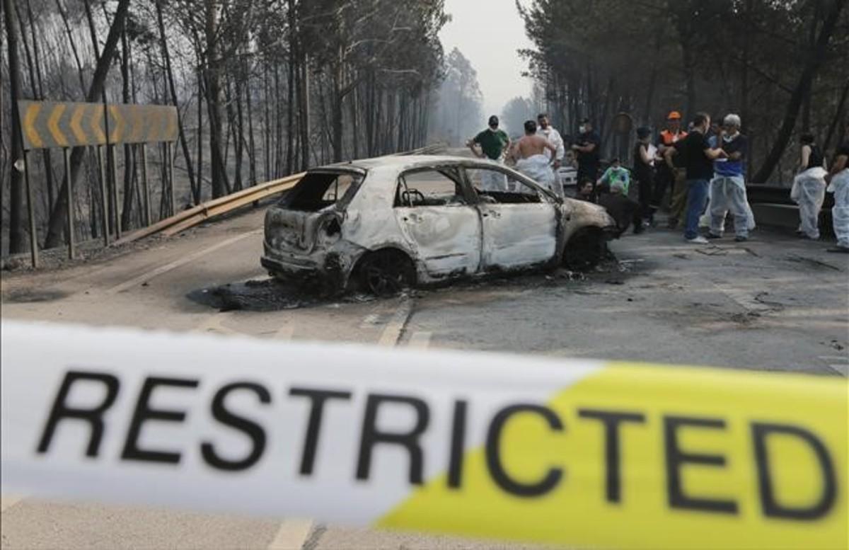 Bomberos y forenses junto a un vehiculo calcinado en la carretera de Castanheira de Pera y Figueiro dos Vinhos