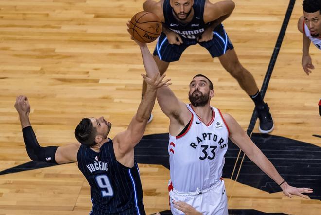 Marc Gasol (d) de Toronto Raptors en acción contra Nikola Vucevic de Orlando Magic durante un partido de baloncesto de la NBA, en el Scotiabank Arena de la ciudad de Toronto (Canadá).