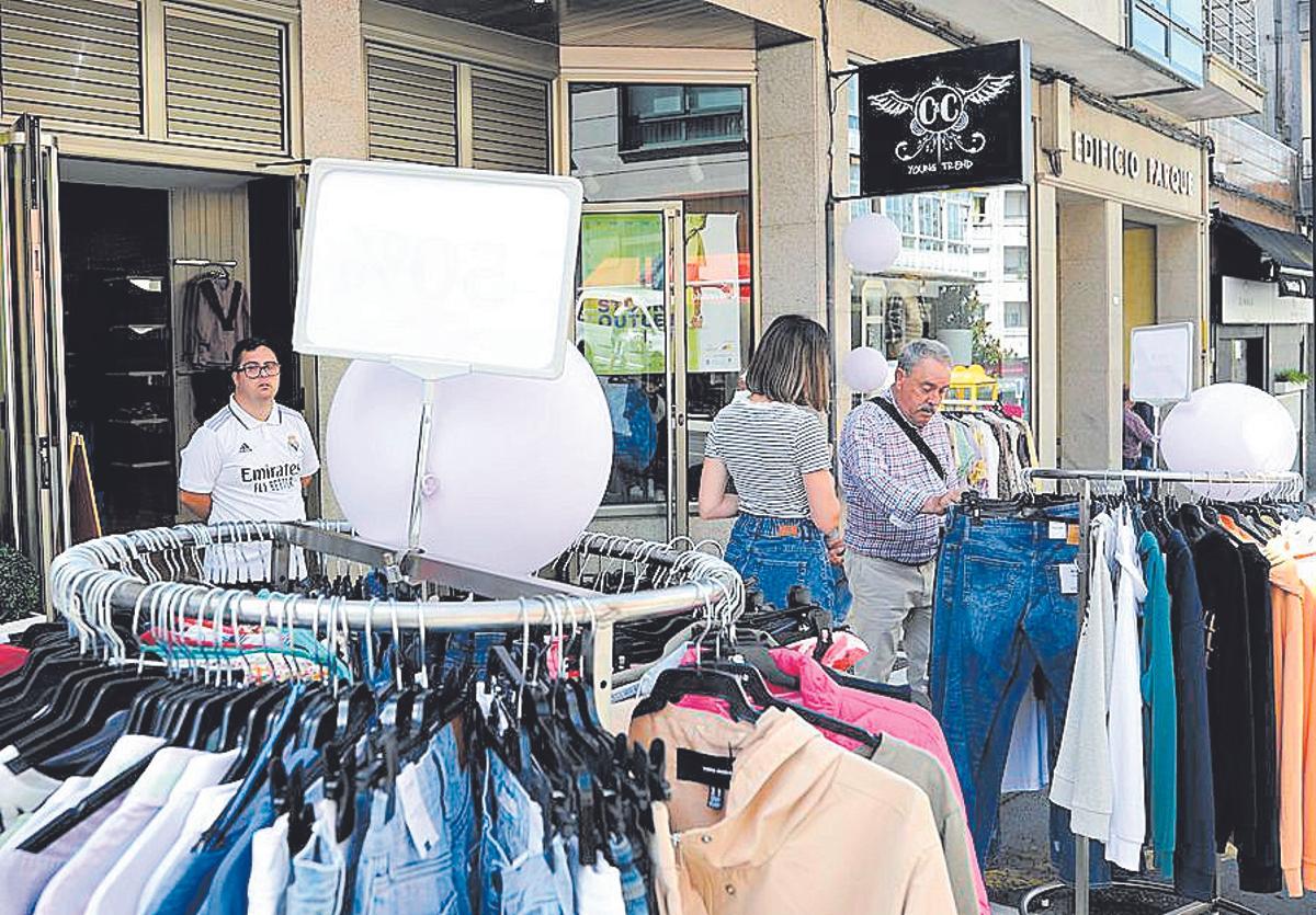 Clientes contemplan ropa con descuentos en una tienda de Lalín.