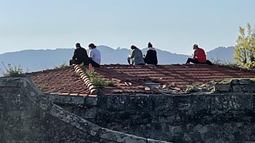 Personas subidas al peligroso mirador sobre la ría de Vigo.