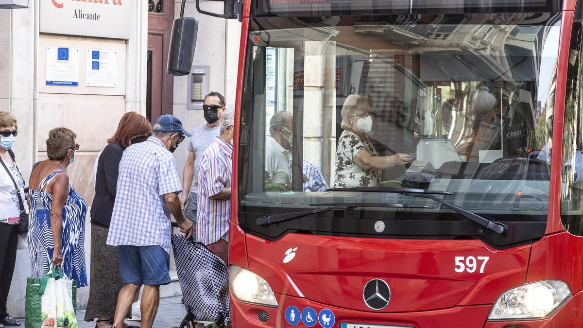 Un grupo de personas hacen cola para acceder al autobús urbano de Alicante