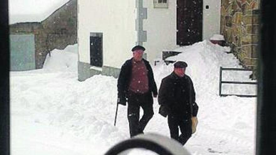 Dos vecinos de Porto avanzan por una calle del pueblo.