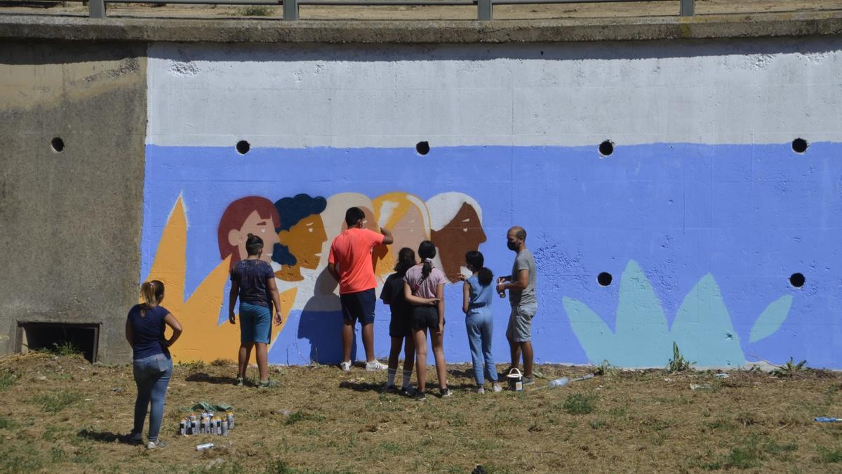Una decena de jóvenes participaron en la confección del grafiti, con el artista zaragozano Pedro Zárate.