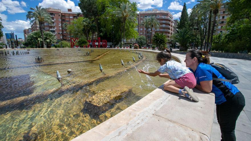 Una mujer y una niña se refrescan con el agua de la gran fuente de la Plaza Circular.  | FRANCISCO PEÑARANDA