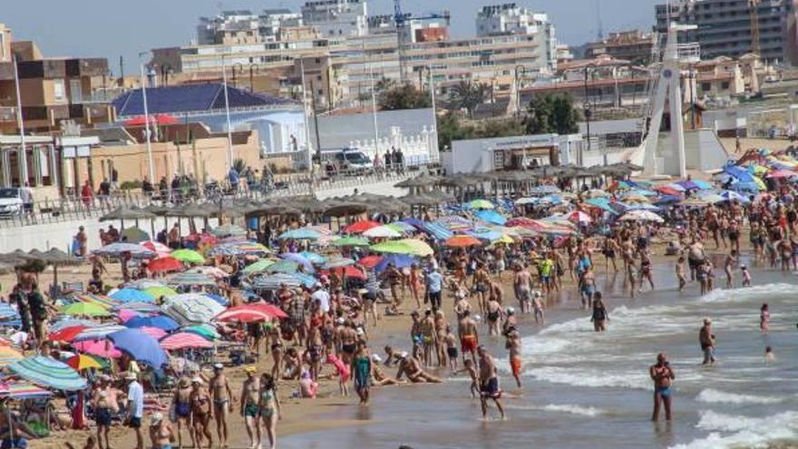 Una imagen veraniega de la playa de La Mata con edificaciones al fondo.