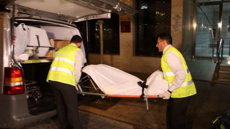 Los trabajadores de la funeraria trasladan el cadáver de la víctima del crimen de la calle Zamora.