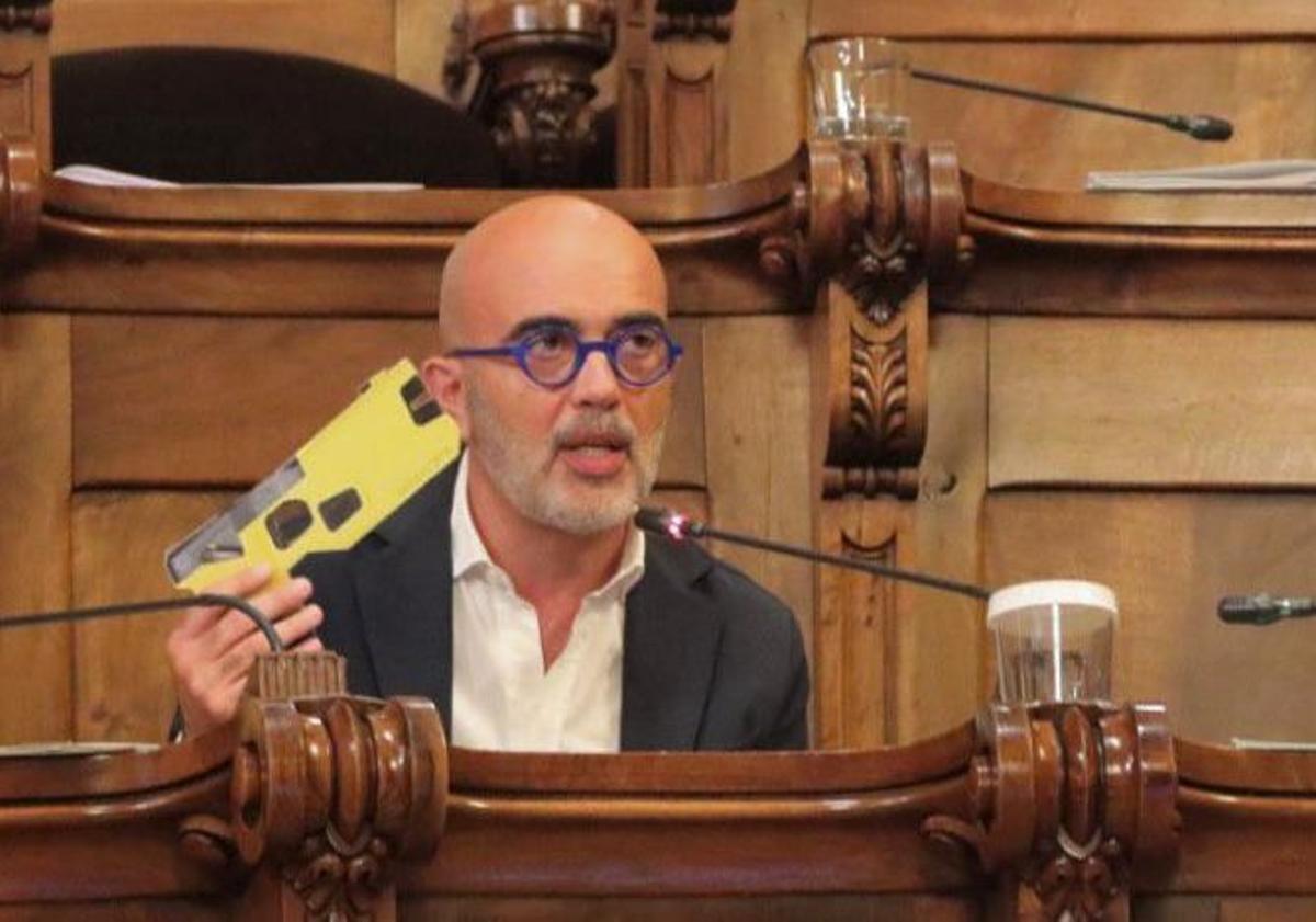 El presidente del grupo municipal del PP en Barcelona, Daniel Sirera, empuña una réplica en cartón de la táser en el pleno municipal