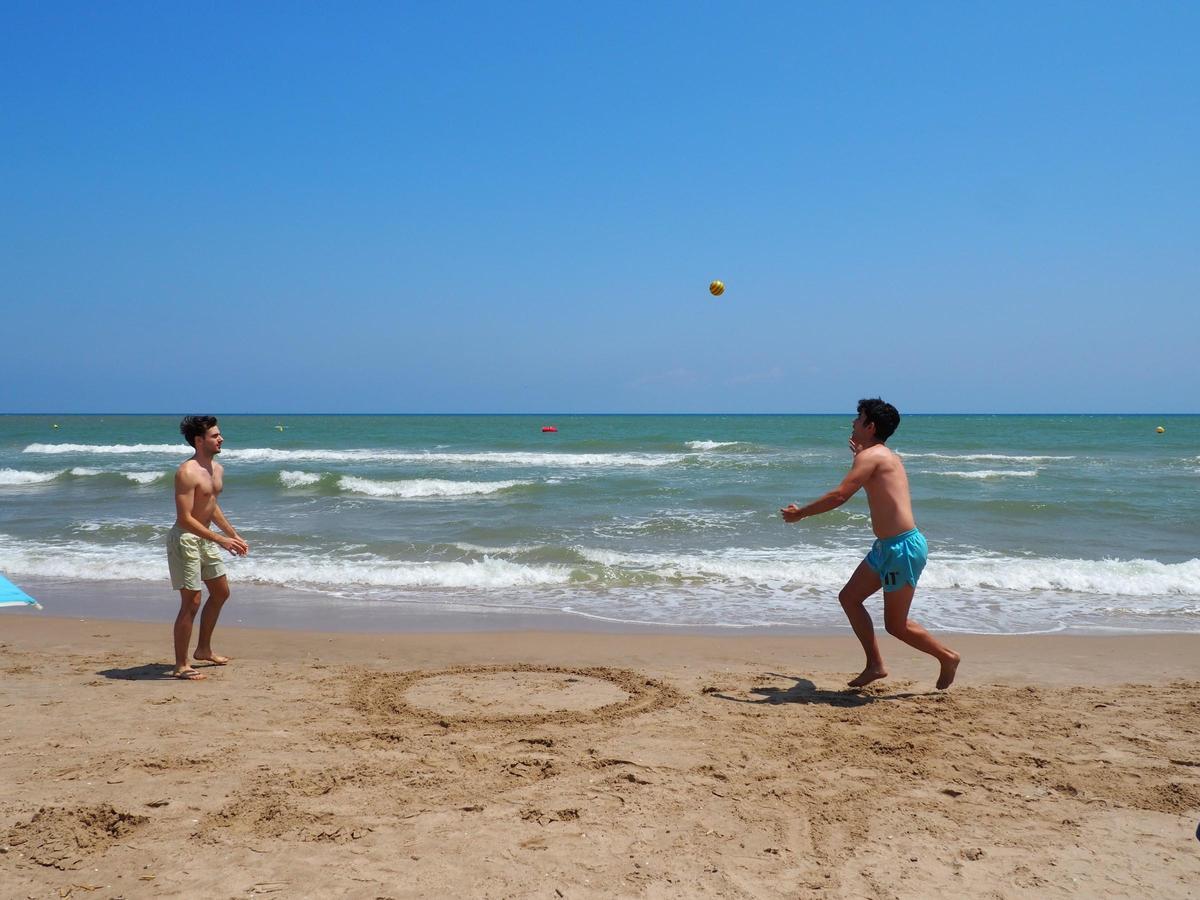 Robert Aguado y Sergio Molina juegan a la pelota mientras se mantiene la prohibición de baño por presencia de residuos fecales en el Perelló.