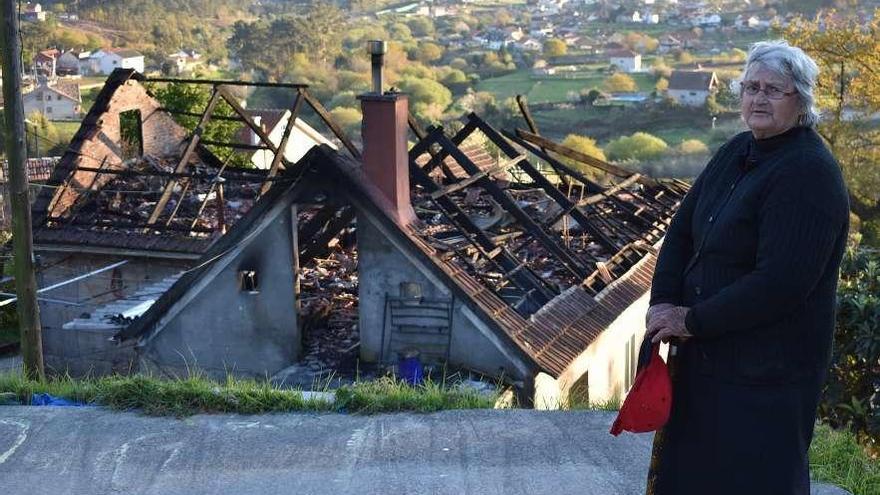 La propietaria de la vivienda, Isabel López, ayer, ante los restos de su casa tras el incendio. // FdV