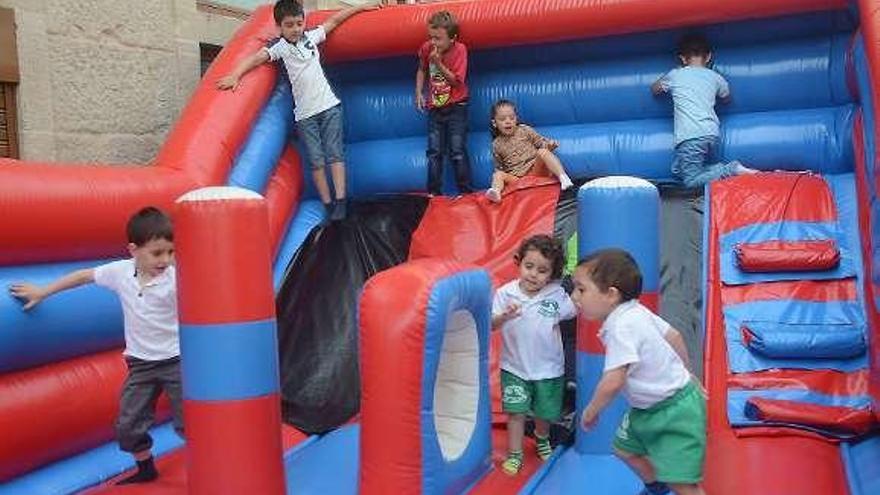 Arriba alumnos de A Xunqueira 1 celebran en el patio de su colegio el fin de curso. Abajo varios niños se divierten en uno de los hinchables instalados en el casco histórico.