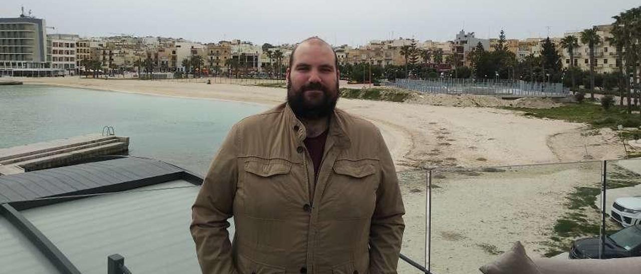 Álvaro Fernández posa delante de una de las playas de la localidad en la que trabaja en Malta. // FDV