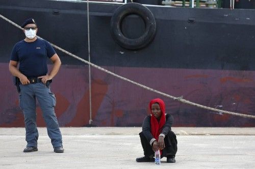 A migrant rests after disembarking from the German navy vessel Schleswig Holstein in the Sicilian harbour of Augusta