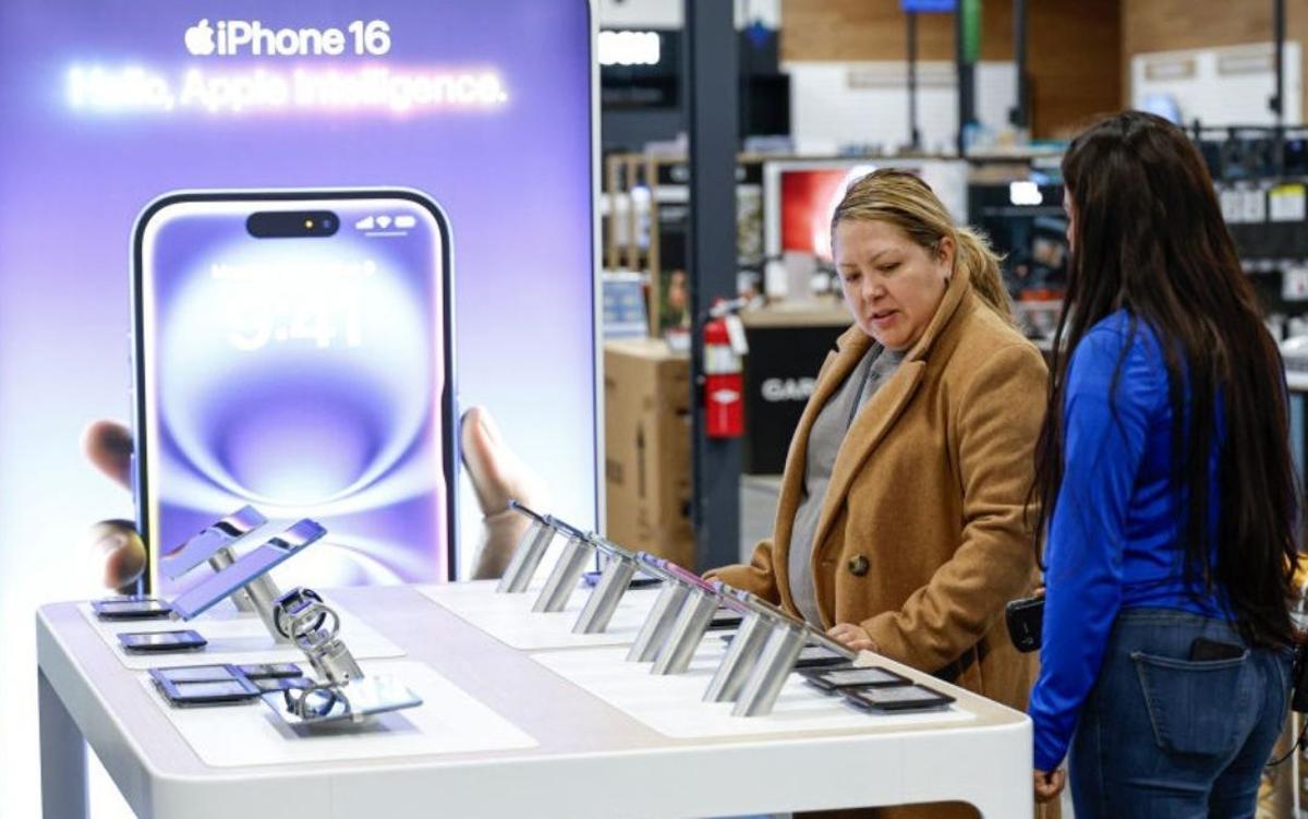 Dos personas informándose sobre el iPhone 16 en una tienda de electrónica.