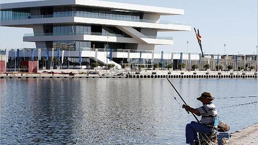 Un hombre pesca en la dársena del Puerto de Valencia frente al Veles e Vents.