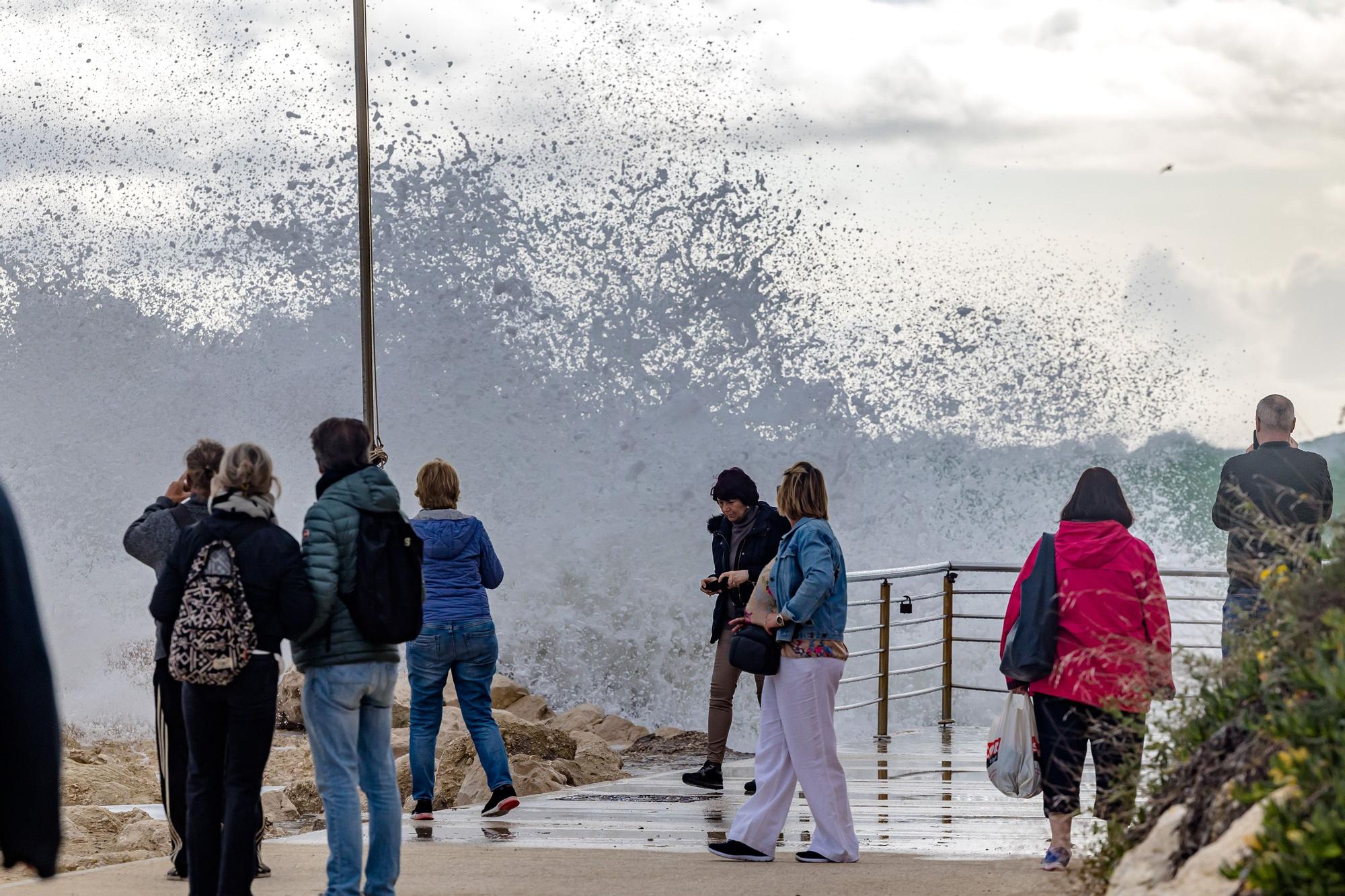 Turistas y paseantes observan el temporal de mar en la Cala de Finestrat