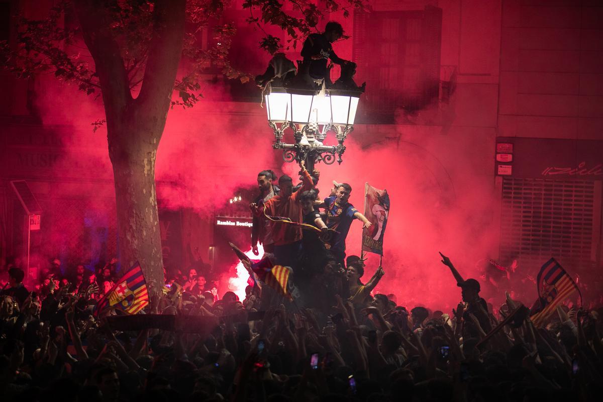 Ambiente festivo en la fuente de Canaletes, donde centenares de aficionados del FC Barcelona celebran el título de Liga.