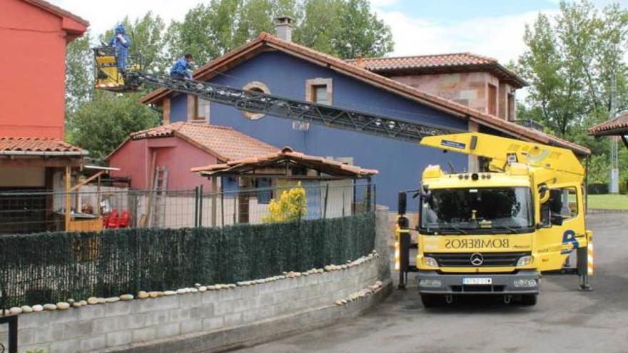 Los bomberos retirando las abejas de la fachada de la vivienda.