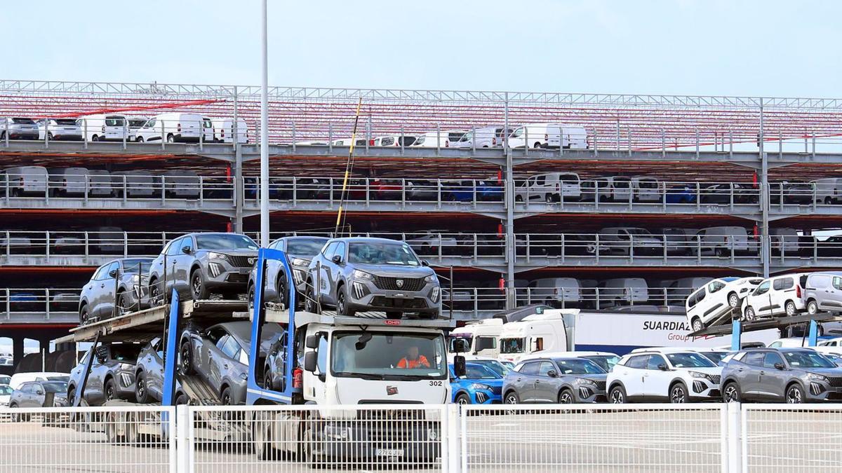 Un camión transporta automóviles de Stellantisen la terminal de Bouzas. Al fondo, el silo.