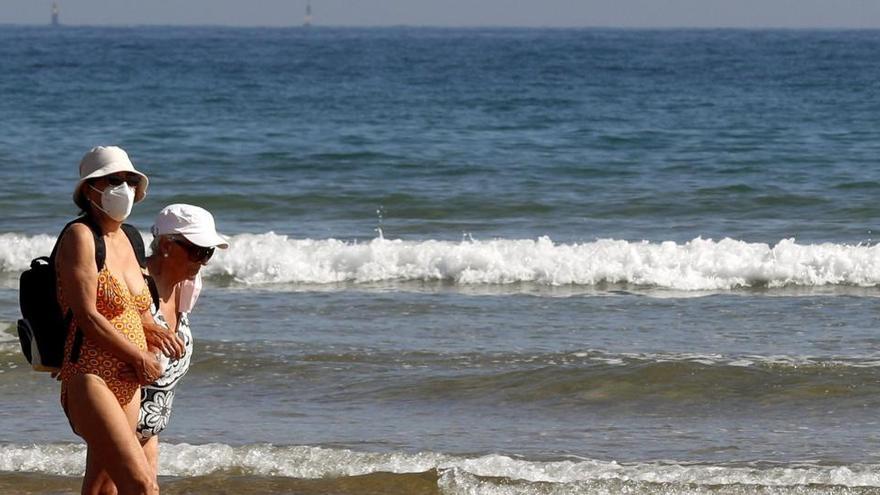 Una mujer con mascarilla en la playa de Gijón.