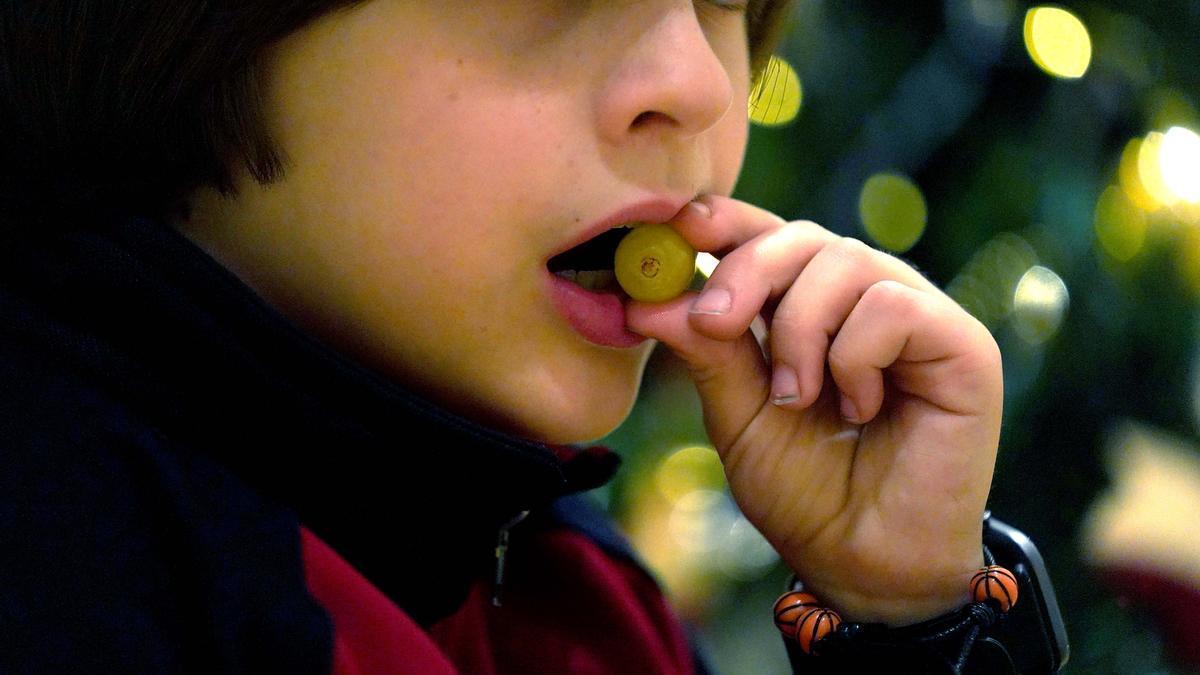 Un niño se lleva una uva a la boca.