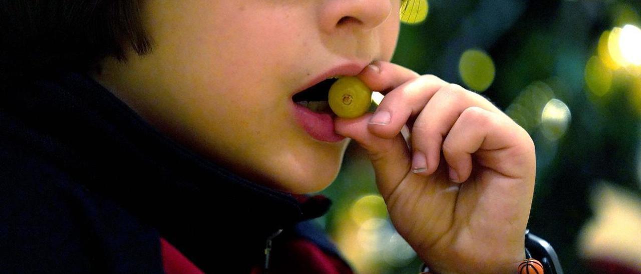 Un niño se lleva una uva a la boca.