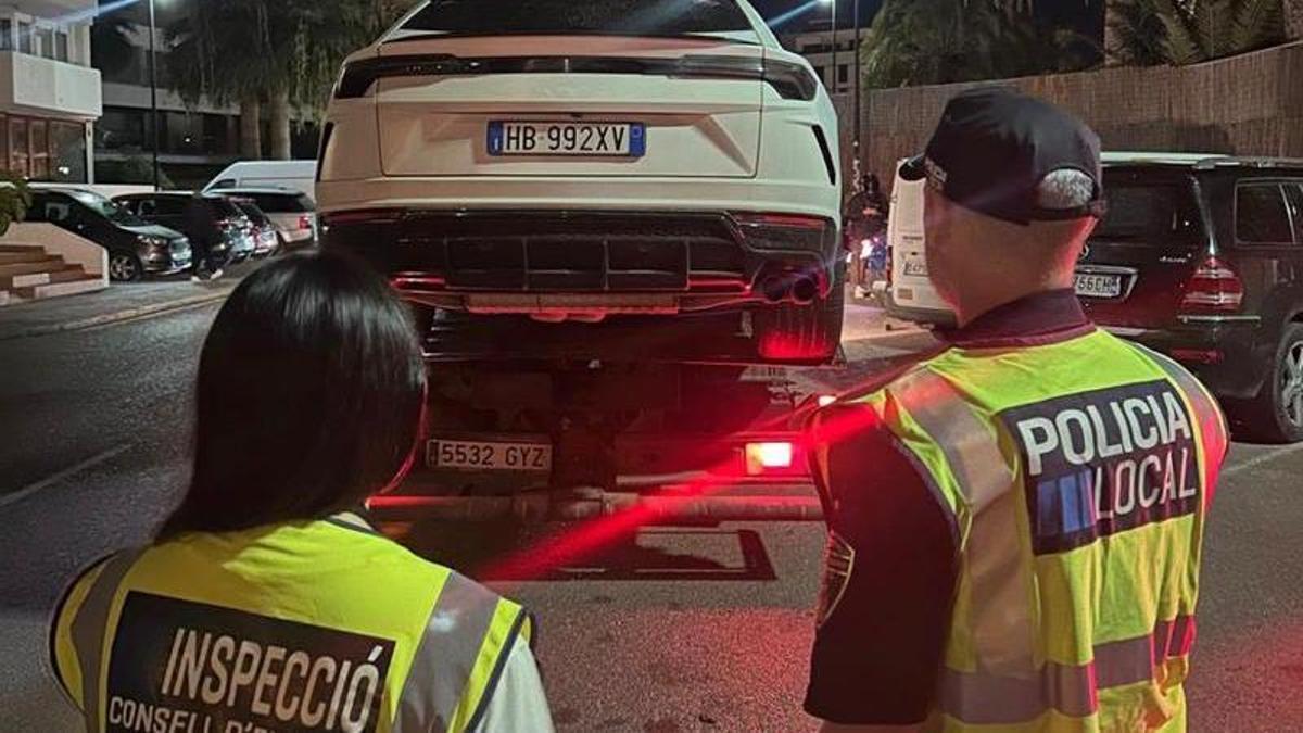 Dos agentes de la Policía Local de Ibiza, mientras un vehículo es trasladado en una grúa.