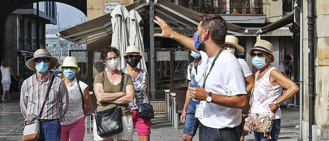 Un grupo de turistas sigue las indicaciones de un guía en la plaza Mayor.