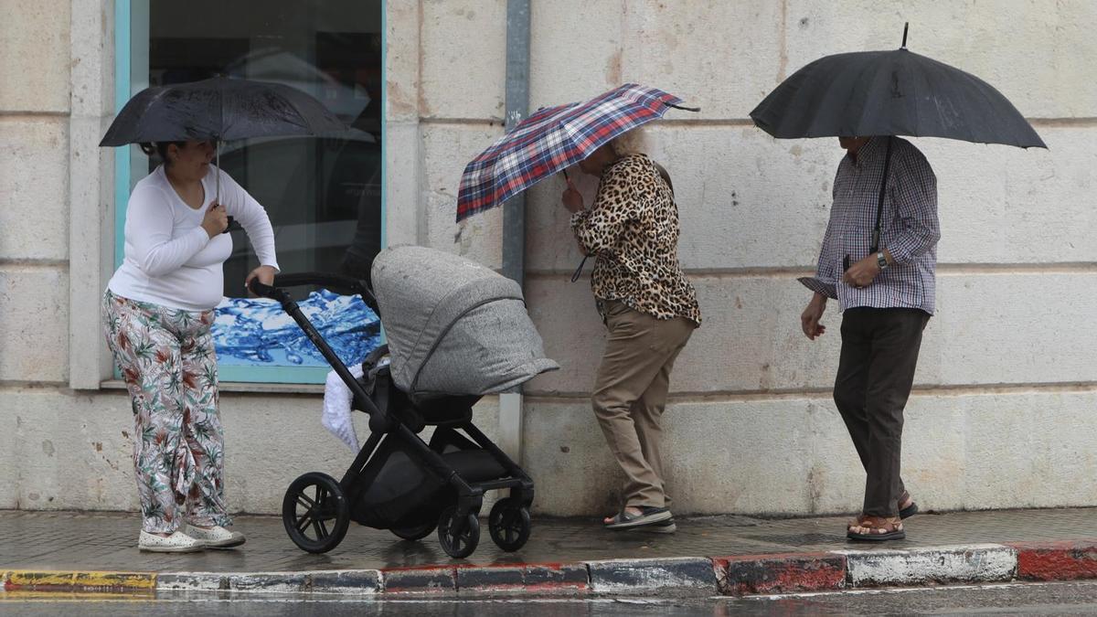 Peatones se resguardan de la lluvia en Sagunt.