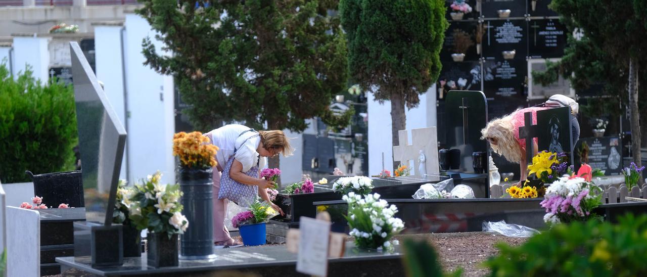Varias mujeres colocan flores en el cementerio de San Lázaro.