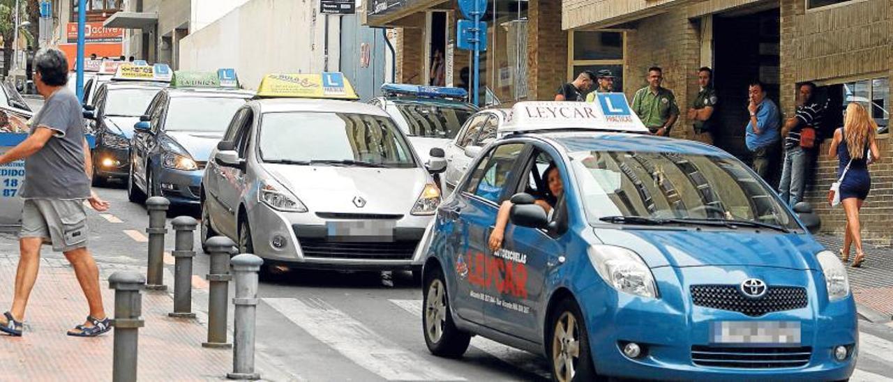 Caravana de protesta formada ayer por coches de autoescuelas a su paso por la calle donde se ubica la Jefatura Provincial de Tráfico en Alicante.