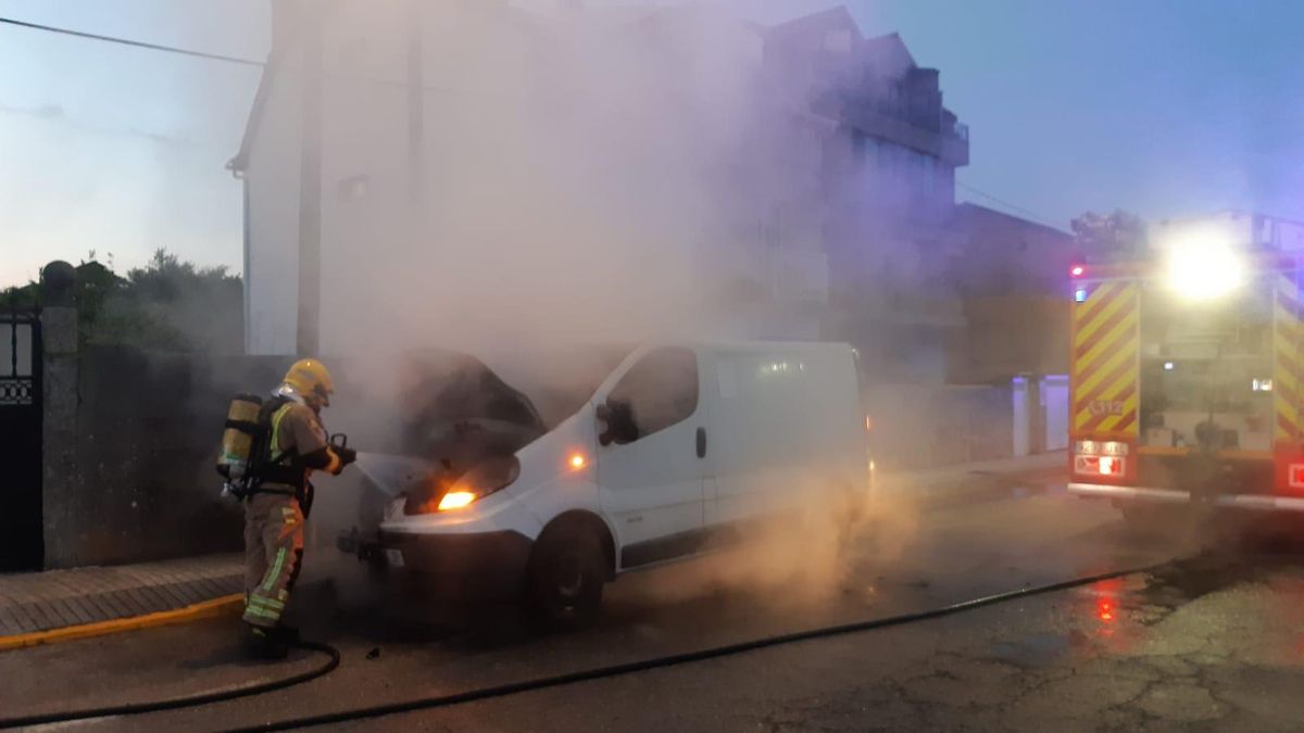 Un bombero extingue las llamas que se originaron en la furgoneta estacionada en A Braña, en la carretera de As Sinas.