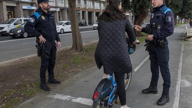 Dos agentes informan a una usuaria de BiciCoruña sobre infracciones. | Casteleiro/Roller Agencia