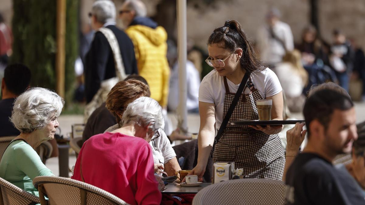 Una camarera atiende una mesa del bar en el que trabaja.