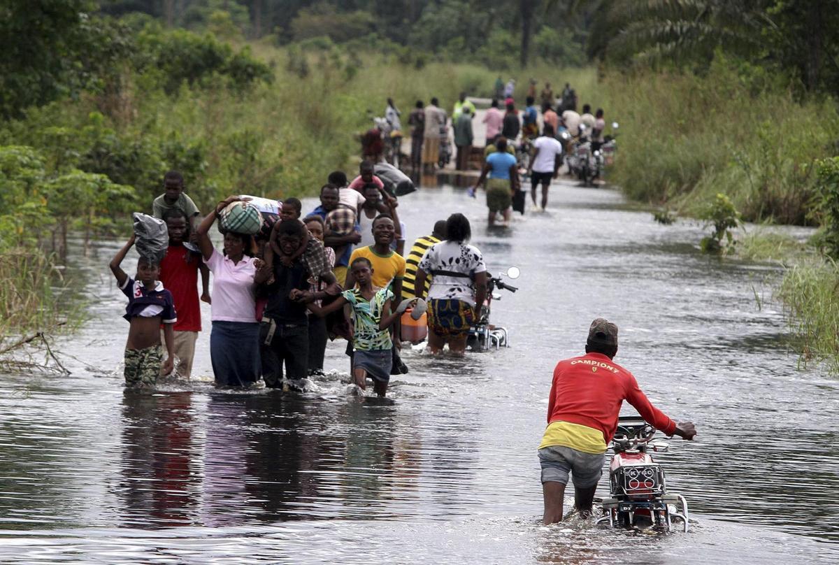 Un grupo de nigerpersonasianos camina por las carreteras inundadas de Okpe, en el delta del Níger, en Nigería.
