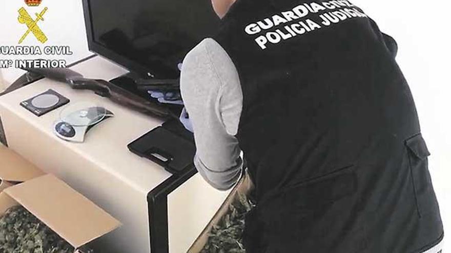 Un guardia civil examina una de las armas intervenidas a uno de los detenidos.