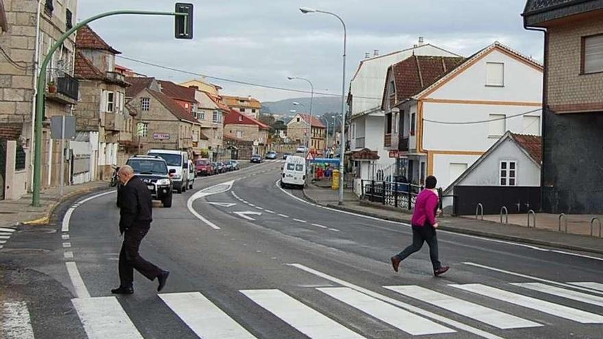 Unos peatones cruzan en el semáforo del centro de Cesantes, en la N-550. // FdV