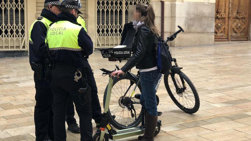 Agentes de la Policía Local de Alicante conversan con una usuaria de un patinete eléctrico, en una imagen reciente tomada en el Casco Antiguo.