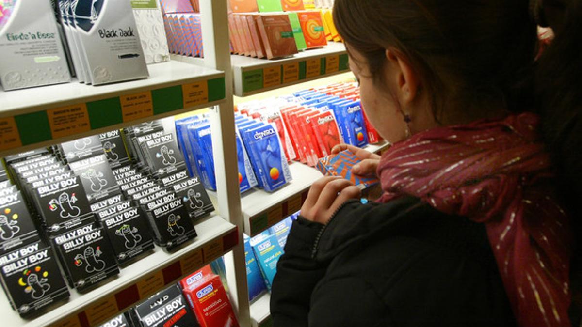 Una chica, frente a un estante repleto de preservativos en una tienda especializada de Barcelona.